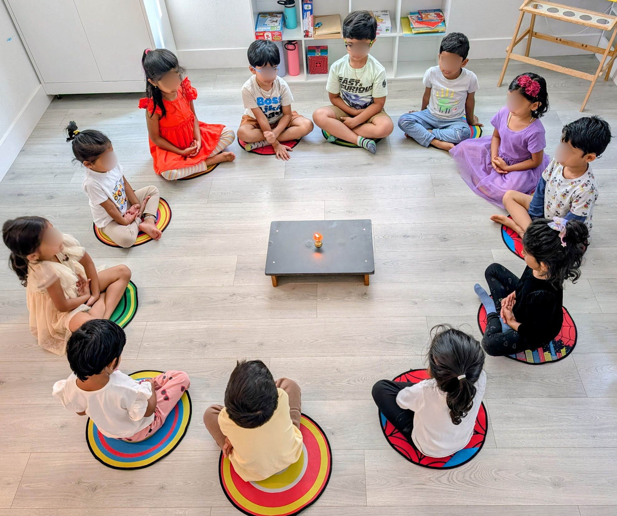 Children practicing Tratak meditation around a lamp